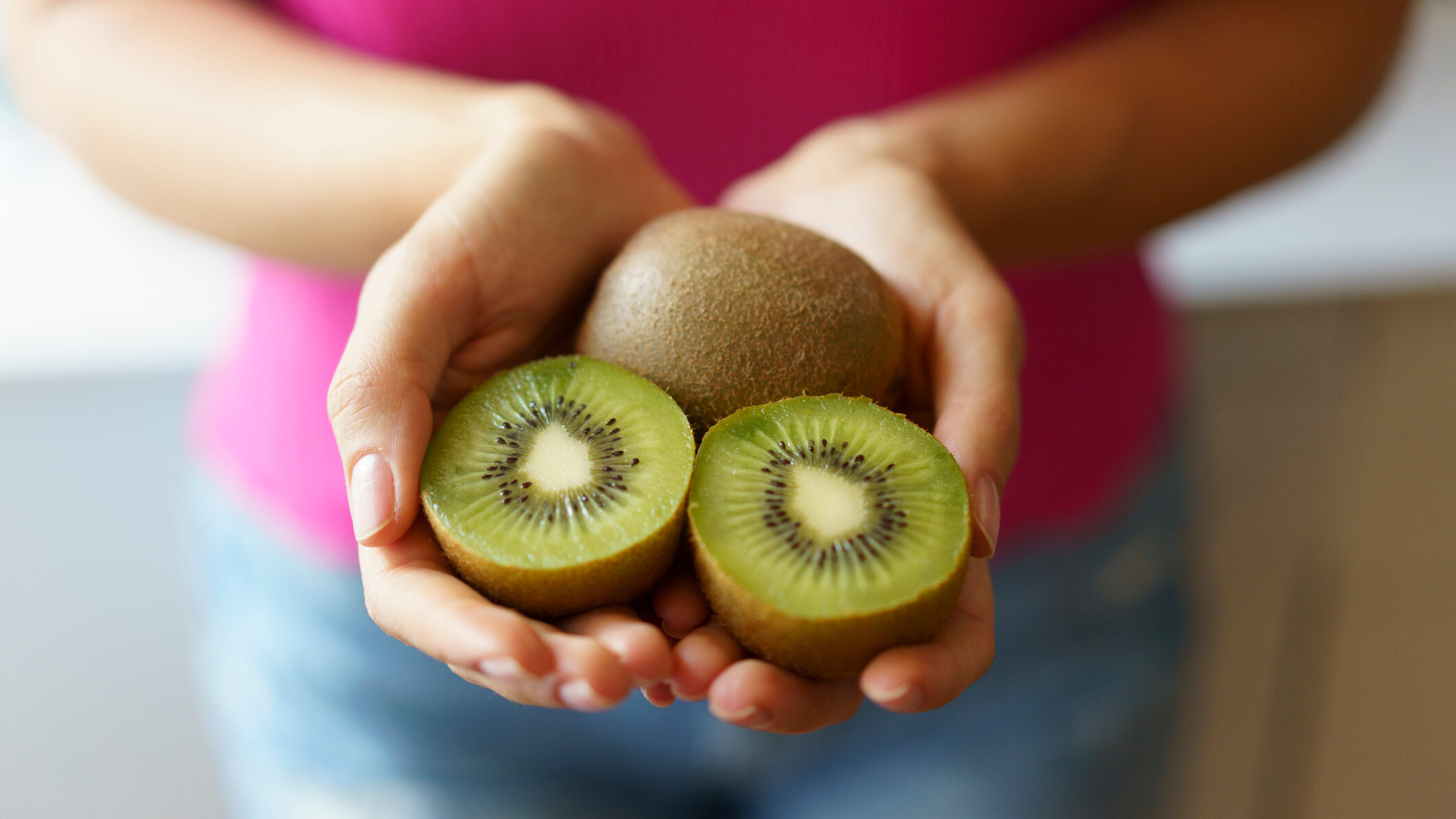 Person holding cut kiwis in hand
