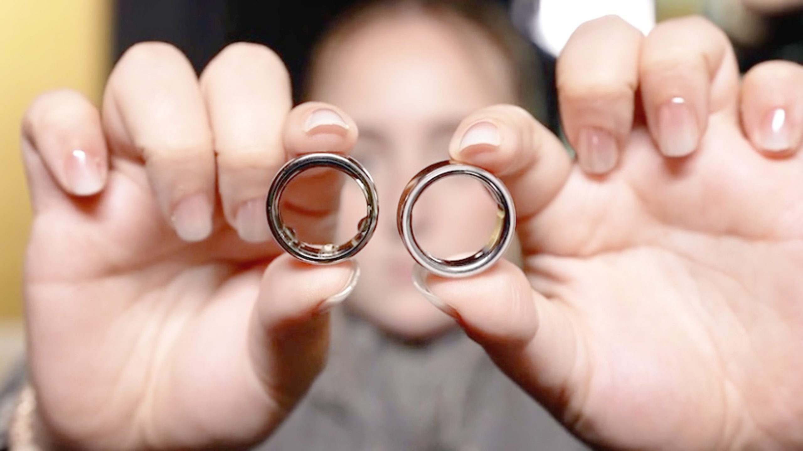 لقطة مقربة لمستخدم يعرض نموذجين من Oura Ring جنبًا إلى جنب