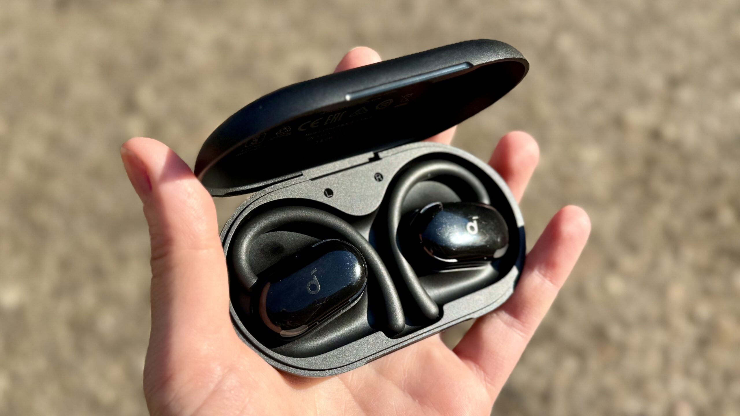 يد تحمل سماعات Soundcore Anker V20i في علبة الشحن الخاصة بها