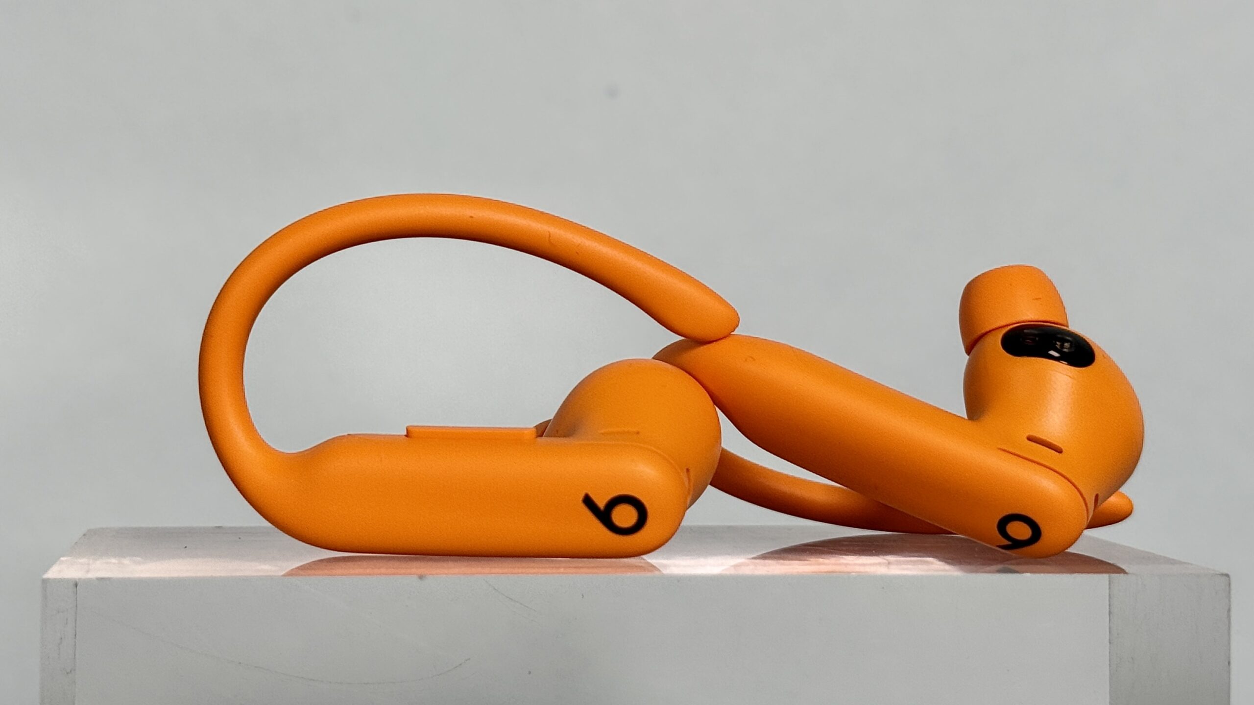 سماعات Beats Powerbeats Pro 2 باللون البرتقالي معروضة جانبياً وتظهر خطاف الأذن