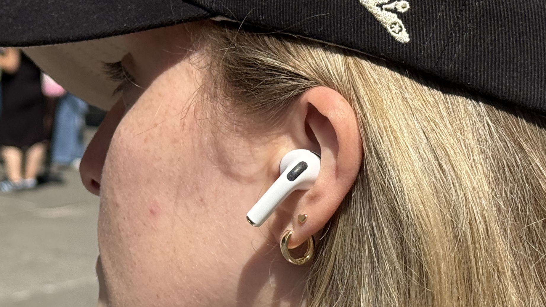 امرأة ترتدي قبعة وسماعات Apple AirPods Pro 3 في الخارج تحت أشعة الشمس