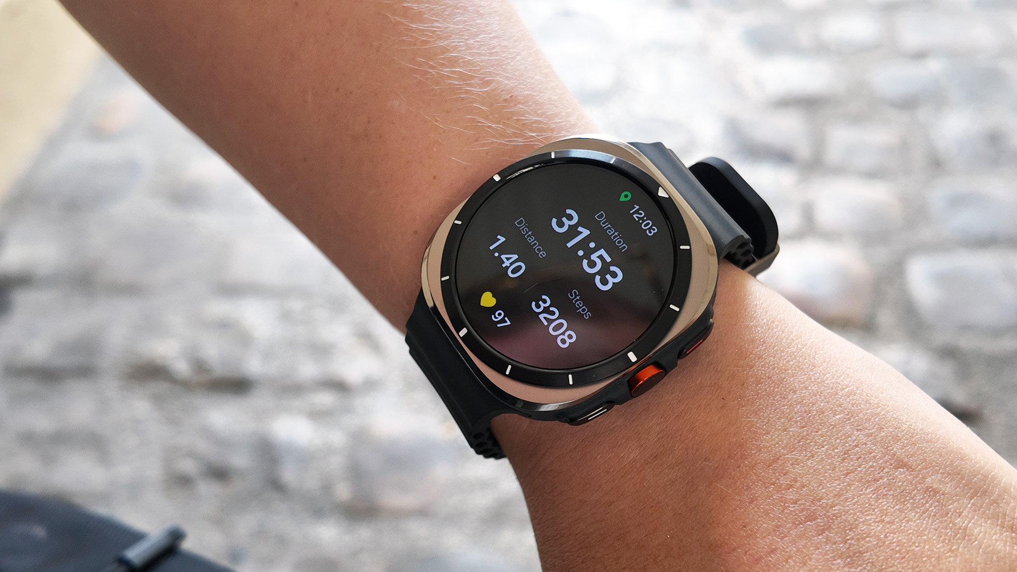 ساعة Galaxy Watch Ultra على معصم شخص تعرض مقاييس التمارين، بما في ذلك المدة والمسافة والخطوات ومعدل ضربات القلب