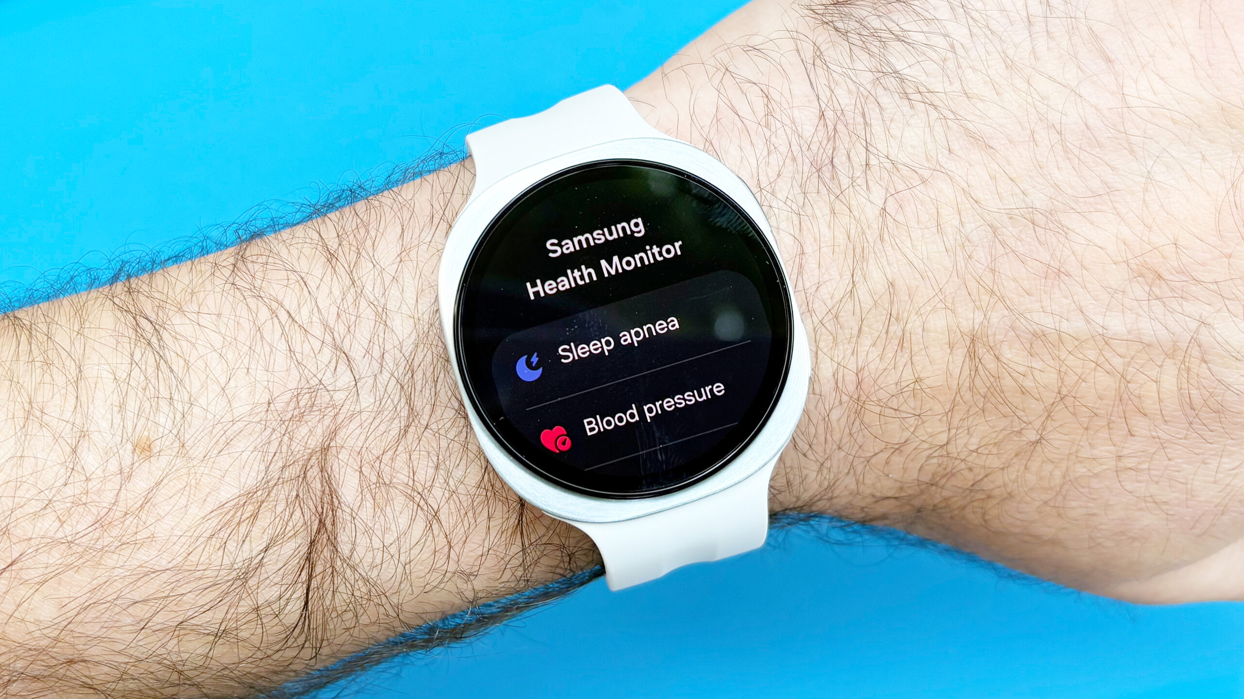 لقطة مقربة لساعة Samsung Galaxy Watch 9 على معصم المستخدم بخلفية زرقاء