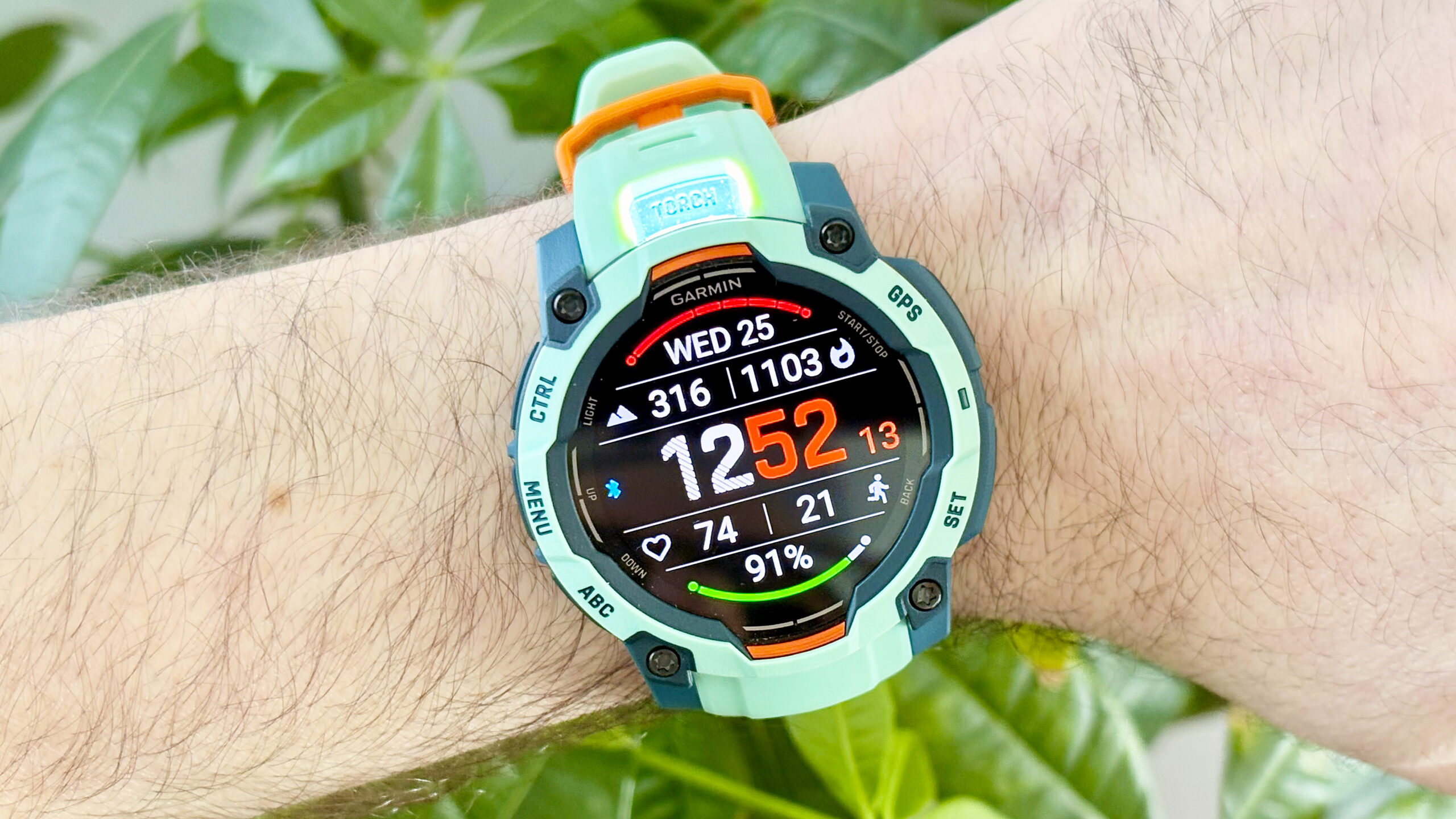 لقطة مقربة لساعة Garmin Instinct 3 تُظهر مصباح LED اليدوي 'Torch' مضاءً من الجزء العلوي لهيكل الساعة