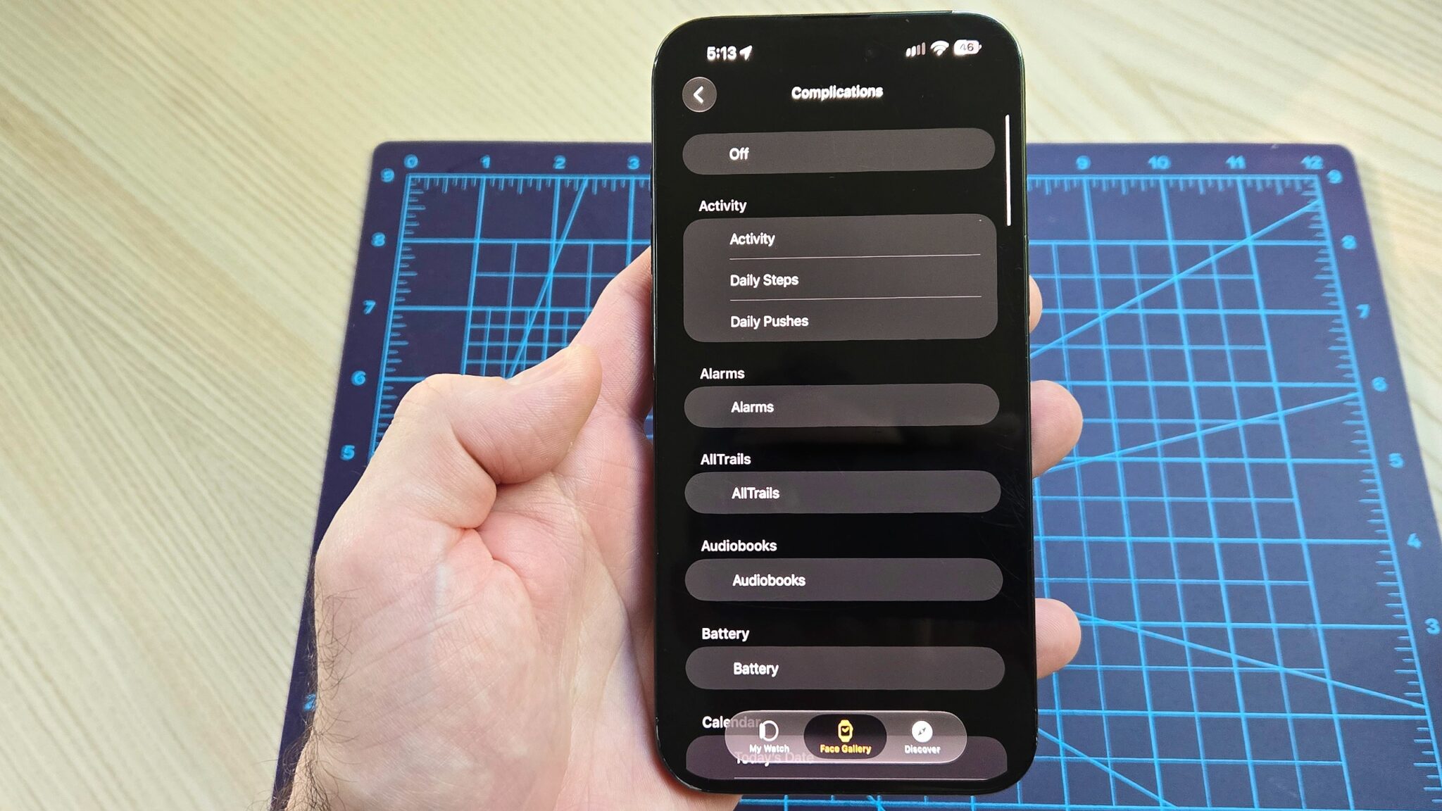 لقطة مقربة لهاتف iPhone 16 Plus توضح كيفية إضافة ويدجت عداد الخطوات الجديد إلى واجهة ساعة Apple Watch الخاصة بك