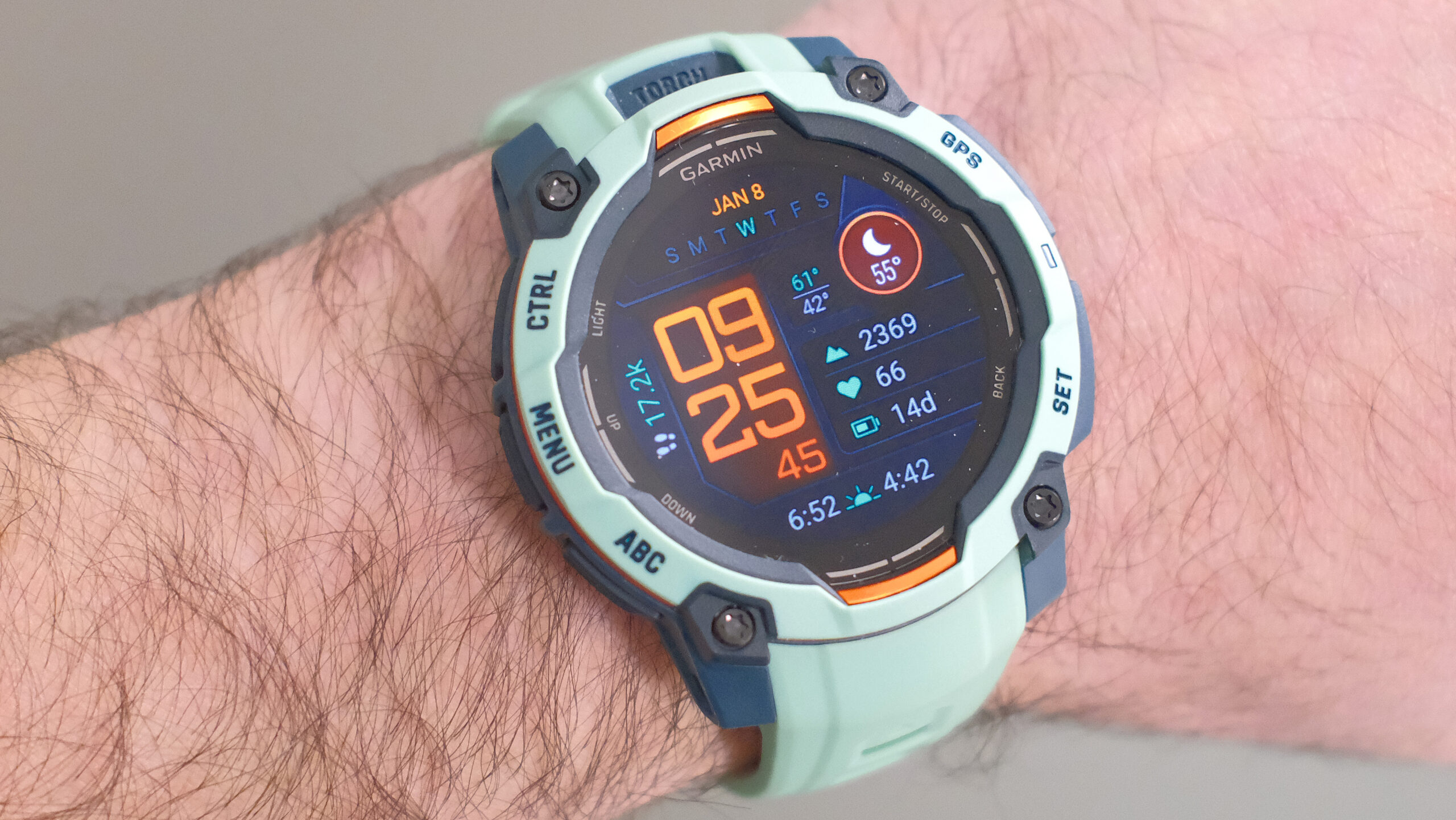 لقطة مقربة لساعة Garmin Instinct 3 GPS الذكية باللونين Neotropic/Twilight مع علبة رمادية وبرتقالية وحزام أخضر بلون رغوة البحر