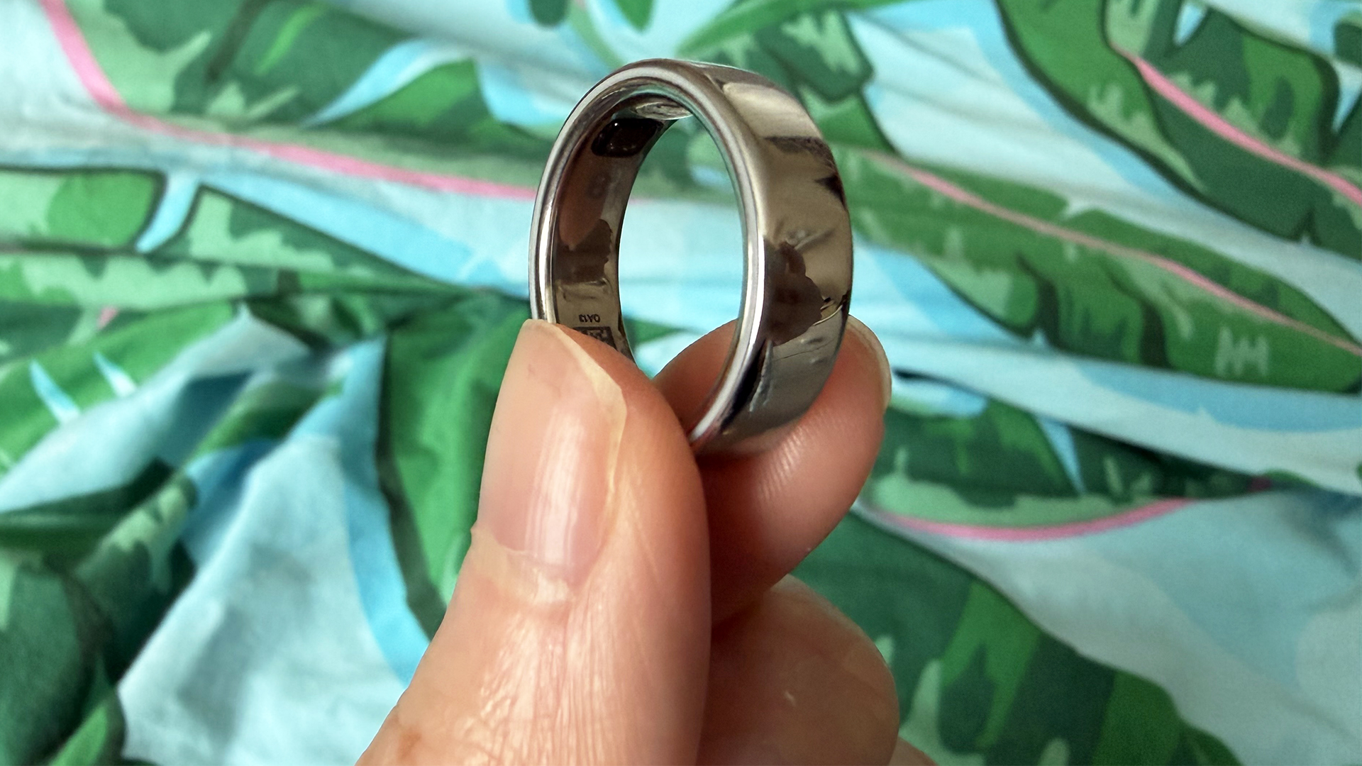 لقطة مقربة لأصابع تحمل خاتم Oura Ring 5 باللون الفضي