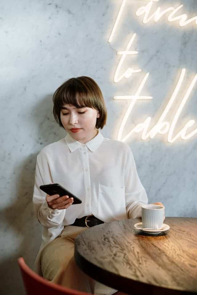 امرأة تستخدم هاتفها في مقهى أثناء عملها على الهاتف